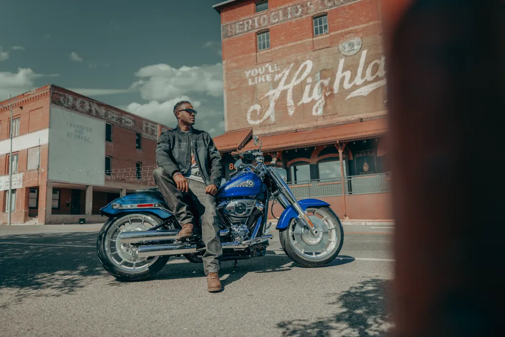 A blue 2025 Harley-Davidson Fat Boy parked side-on in a street, its rider leaning on it