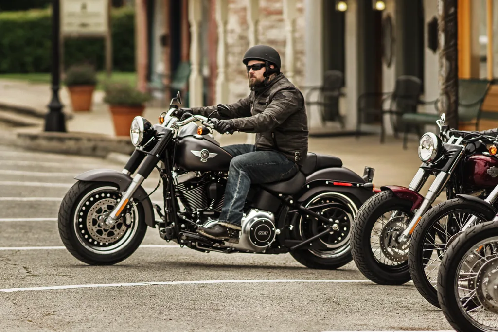 A rider on a black 2016 Harley-Davidson Fat Boy Lo, with part of a Softail Slim visible alongside.