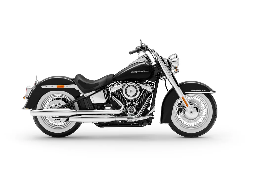 Right-side studio view of a black 2020 Harley-Davidson Softail Deluxe, with whitewall tyres, chrome exhaust and rider footboards.