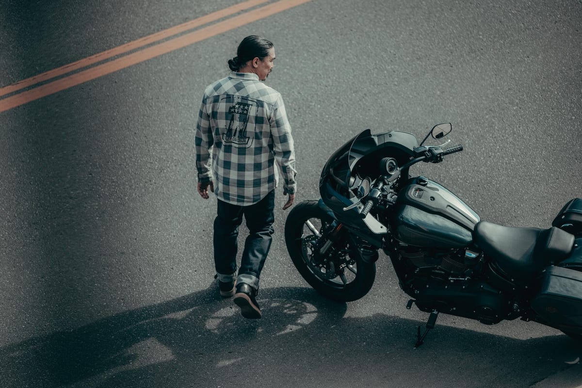 A rider walking to a parked Harley-Davidson Low Rider ST on an open road
