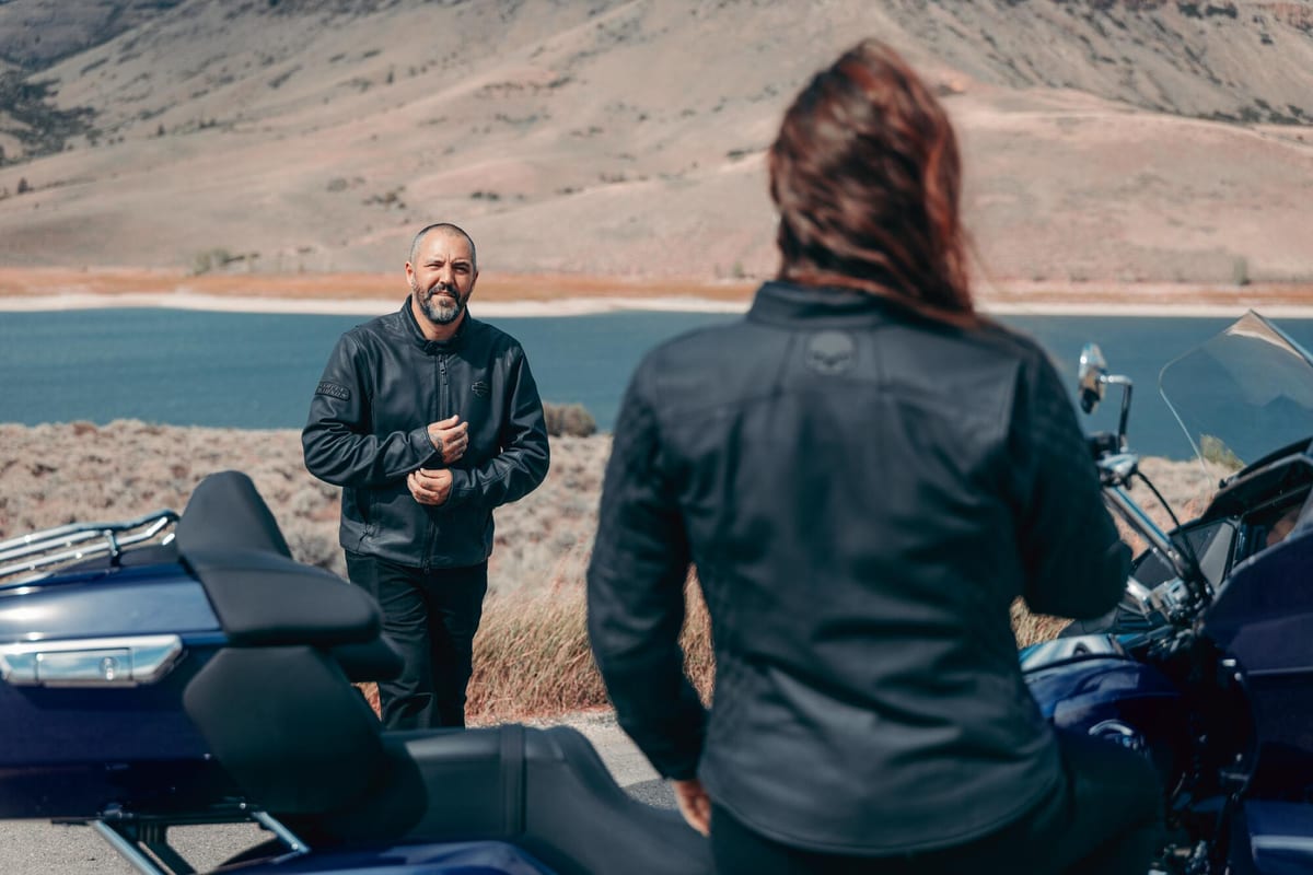 Two Harley-Davidson riders beside a Road Glide touring motorcycle