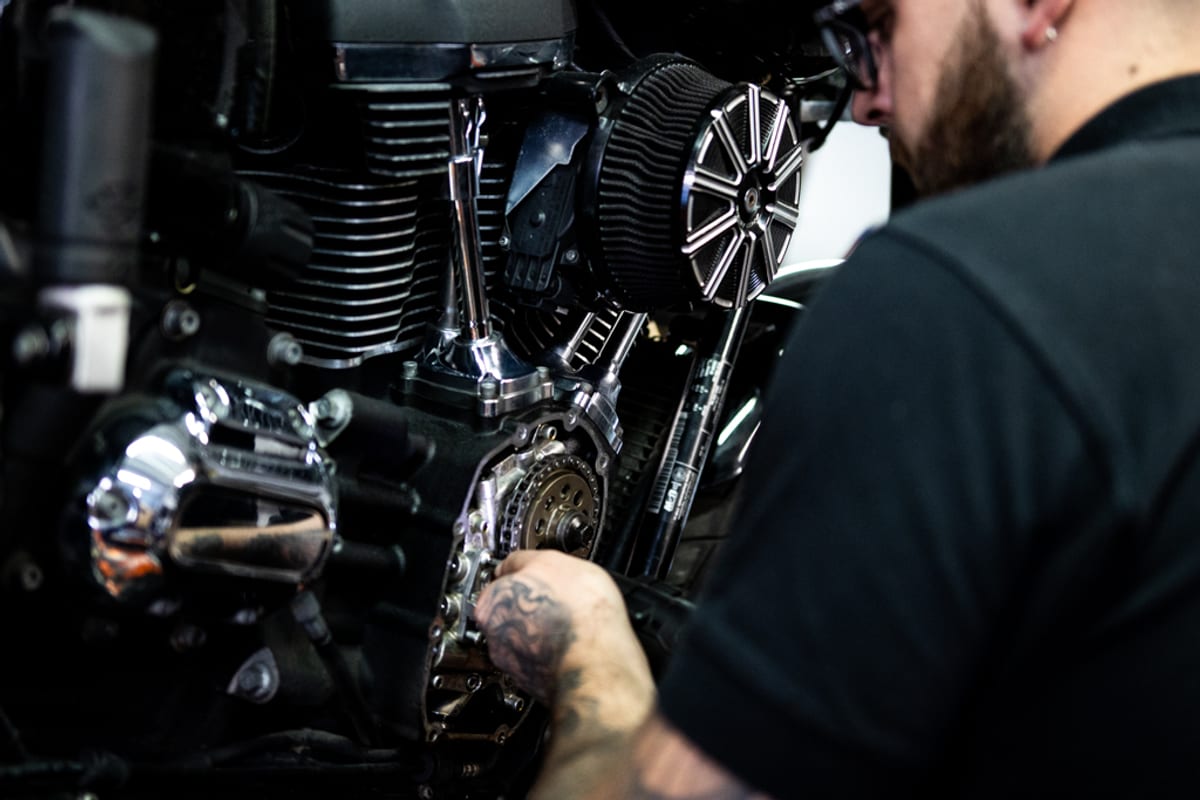A mechanic working on a Harley-Davidson cam chest with the air cleaner exposed