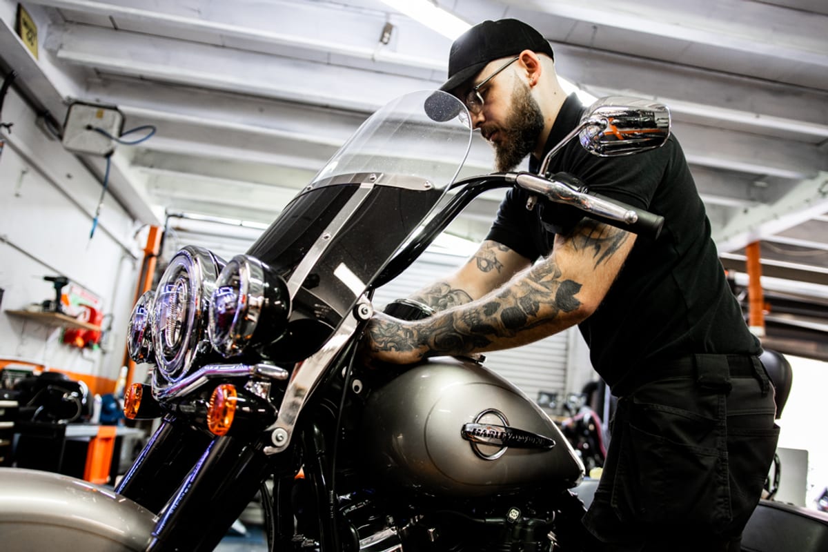 A Harley-Davidson Softail on the bench with a technician working through routine service checks